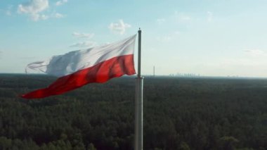 Polonya bayrağı. Polonya ulusal kırmızı ve beyaz bayrağı rüzgarda gururla dalgalanır. Ufukta, tanınmış Varşova gökdelenlerinin arka planında bir bayrak direğinde..