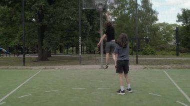 İki arkadaş basketbol antrenmanı yapıyor, takım çalışması ve arkadaşlık gösteriyor. Oyuncular basket, kaygısız oyun ve gençlik arkadaşlığını paylaşarak şut attılar. Egzersiz, işbirliği ve spor..