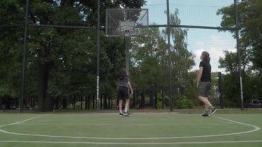 Basketbol sahasında iki adam basket atıyor, potaya girmeye çalışıyorlar. Top potayı ıskaladı, çembere ya da arka tahtaya çarptı. Iskalamalarına rağmen ateş etmeye devam ediyorlar..