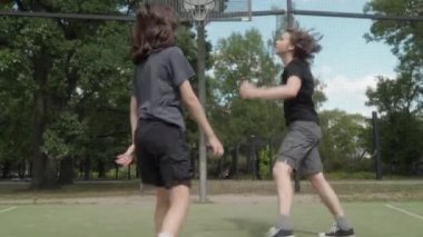 İki çocuk açık hava sahasında potaya basket topu atıyor. Top tekrar tekrar ıskalıyor, çembere çarpıyor ya da arka tahtadan sekiyor. Vazgeçmezler ve tekrar tekrar denemeye devam ederler..