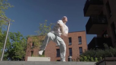 Dinamik bir sokak dansçısı, şehir ortamında, serbest stil hip-hop koreografisini sergileyerek enerjik hareketler sergiler. Sokak kültürü, kendini ifade etme ve halka açık bir yerde modern dans..