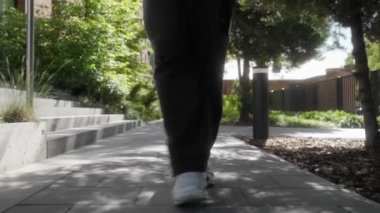 Neşeli bir adam dans eder ve kaldırımda zıplar, ritim ve kendine güvenle hareket eder. Onun kaygısız hareketleri ve pozitif enerji gösterisi mutluluk ve eğlence rahat, güneşli bir şehir parkında.