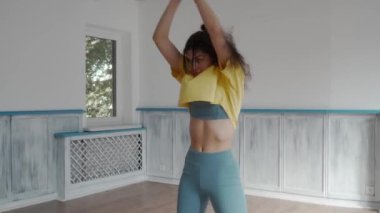 Bir kadın egzersiz stüdyosunda yoga minderinde esneklik egzersizi yapıyor. Eğiliyor, dönüyor, esniyor, kontrol ve hareket kabiliyetini gösteriyor. Yoga, esneme ve spor rutininin gösterimi.