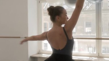 Balerin, bale stüdyosunda aynanın önünde zarif bir şekilde bir bacağının üzerinde dönüyor. Dansçı, dans eğitimi sırasında dönüşler ve dönüşler yapar..