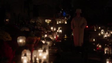 Kasım 'da Azizler Günü' nde mezarlıkta cenaze mumları ve çiçekler. Eski sevdiklerinin anısına mezarları yanan mezar taşı fenerleriyle süslemek Hristiyan Katolik geleneğidir..