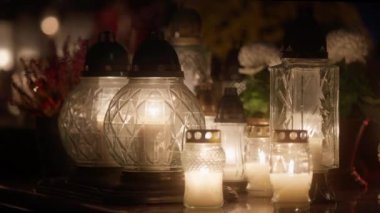 Kasım 'da Azizler Günü' nde mezarlıkta cenaze mumları ve çiçekler. Eski sevdiklerinin anısına mezarları yanan mezar taşı fenerleriyle süslemek Hristiyan Katolik geleneğidir..