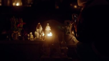 Kasım 'da Azizler Günü' nde mezarlıkta cenaze mumları ve çiçekler. Eski sevdiklerinin anısına mezarları yanan mezar taşı fenerleriyle süslemek Hristiyan Katolik geleneğidir..