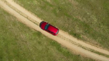 Kırmızı bir araba tozlu toprak bir yolun izlerinden vahşi tarlalarda ve bozkırlarda geçiyor. Macera arayışında keşfedilmemiş yollarda bir yolculuk.