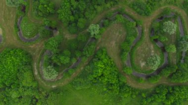 Ağaçlar ve çalılar arasındaki çayırlarda dolambaçlı bir nehir yatağı var. Çeşme suyu olan küçük bir dere yeşil tarlalardan ve saman yapım alanlarından akar. Nehir kıyısında yemyeşil bitkiler yetişiyor..