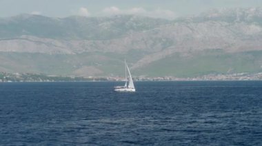 Bir yelkenli yatı, dağların arka planına karşı denizde yol alır. Adriyatik kıyısı boyunca seyrüsefer. Hırvatistan adaları arasında Adriyatik Denizi 'ni geçmek.