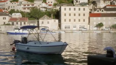 Deniz kıyısındaki eski bir kasabanın rıhtım güvertesi boyunca kıyıya demirlemiş tekneler. Hırvatistan 'ın Brac (Bra) adasındaki Pucisca (Puia) liman kasabasının konut binaları ve sokakları.