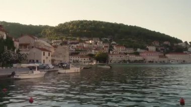 Deniz kıyısındaki eski bir kasabanın rıhtım güvertesi boyunca kıyıya demirlemiş tekneler. Hırvatistan 'ın Brac (Bra) adasındaki Pucisca (Puia) liman kasabasının konut binaları ve sokakları.