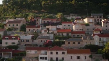 Deniz kenarındaki bir yamaçtaki turist kasabasının rıhtımı. Hırvatistan 'ın Brac (Sütyen) adasındaki Pucisca (Puia) liman kasabasında kiremit çatılı ve büyüleyici sokaklara sahip taş evler.