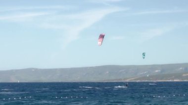 Uçurtmacılar rüzgarı yakalayıp Hırvatistan 'ın Brac (Bra) adasındaki Zlatni Rat plajı boyunca uçurtma ve uçurtma sörfü yapıyorlar. Aşırı su sporları. Adriyatik kıyısında yaz turizm sezonu.