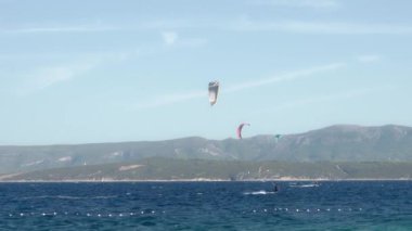 Uçurtmacılar rüzgarı yakalayıp Hırvatistan 'ın Brac (Bra) adasındaki Zlatni Rat plajı boyunca uçurtma ve uçurtma sörfü yapıyorlar. Aşırı su sporları. Adriyatik kıyısında yaz turizm sezonu.