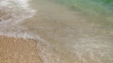 Hırvatistan 'ın Sütyen adasının kumlu çakıl taşlı sahilinde beyaz deniz dalgaları süzülüp beyaz köpüklere dönüşüyor. Adriyatik kıyısında turizm ve plaj eğlencesi.