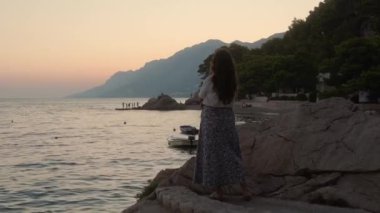 Akşamüstü alacakaranlıkta taş bir iskelede tek başına duran düşünceli bir kız rüyasında denize bakıyor. Hırvatistan 'ın Adriyatik kıyısında gün batımına romantik bir bakış atan bir kadın.