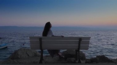 Gün batımından sonra deniz kenarındaki bir bankta tek başına oturan bir kız hayal kurar ve umarım sakin denize bakar. Hırvatistan 'ın Adriyatik kıyısında günbatımını seyreden bir kadın görülüyor..