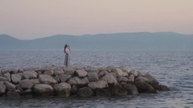 Düşünceli bir kız sabahın erken saatlerinde taş bir iskelede tek başına, rüyasında denize bakıyor, şafakla buluşuyor. Hırvatistan 'ın Adriyatik kıyısında romantik bir şekilde güneşin doğmasını bekleyen bir kadın.