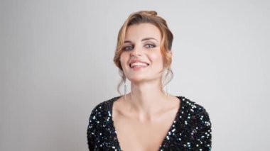 Kusursuz makyajı ve şık updosu olan pullu bir gece elbisesi içindeki güzel bir kız beyaz bir arka plana karşı kibarca poz veriyor ve neşeli bir öpücük yolluyor. Sevgililer Günün kutlu olsun.!