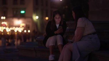 Vücut tipleri farklı olan iki kadın arkadaş, biri zayıf ve diğeri kilolu, geceleri şehir meydanında oturup konuşuyorlar..
