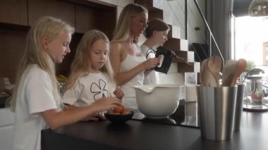 Anne ve kızları mutfakta malzemeleri hazırlıyorlar. Genç kızlar annelerinin rehberliğinde yumurta kırarlar. En büyük abla tek eliyle yumurtayı kırdığını ustalıkla gösteriyor. Aile bağları, aşçılık becerileri..
