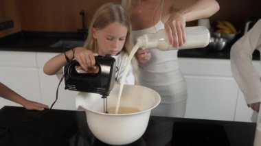 Aile krep hamuru yapar: anne süt döker. Küçük kız el çırpıcısıyla karışıyor, sonra yorulduğunda ablasından yardım istiyor. Kardeşler sırayla yemek hazırlar, takım çalışmasını gösterirler..