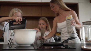 Anne, kızlarına fırını nasıl kullanacaklarını ve krep pişirmek için tavayı nasıl hazırlayacaklarını gösterir. Kızların dikkatle izlediği sıcak tavaya ghee ekliyor, gerekli aşçılık adımlarını öğreniyor..