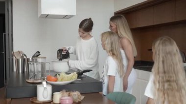 En büyük kızı krep hamurunu, annesi ve küçük kız kardeşlerinin izlediği bir el çırpma makinesiyle ustalıkla karıştırmayı bitiriyor. Yumuşak vurucu artık yemek yapmaya hazır. Mutfakta aile çalışması..