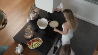 Annem ilk krepi dikkatlice fırında pişirir. Kenarlarını kontrol etmek için bir spatula kullanıyor, ısıyı ayarlıyor ve kızları kızarma sürecini izlerken pişirmesine izin veriyor..