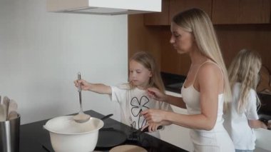 Küçük kız annesinin rehberliğinde krep pişirmeyi öğreniyor. Bir kepçeden çıkan hamuru dikkatlice kızgın bir tavaya döküyor, sonra da krep yapmak için yayıyor. Aile yemeği dersi..