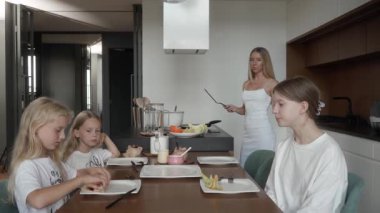 Bir anne üç kızıyla iletişim kurarken onlar da modern mutfaklarında ev yapımı krep kahvaltısının tadını çıkarıyorlar. Aile bağları, iletişim ve evde paylaşılan yemek saatlerine odaklanın.