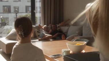 Anne yemeği bitirirken bir aile evde dinlenir. Buharlı mısır bir kızın oturduğu masada; baba ve diğer iki kız kanepede uzanır, ortak bir yemek ve sıcak bir aile zamanı bekler.