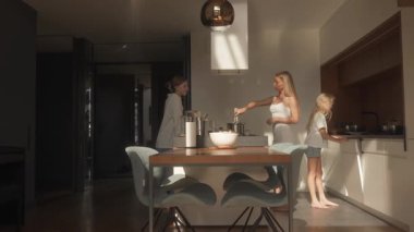 Annem sobada yemek pişirir, yemek karıştırır ve mutfak adasının orada büyük kızıyla sohbet eder. Küçük kız yemekten sonra kirli tabağını bulaşık makinesine koyarak yardım ediyor..