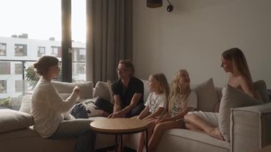 Büyük kızı hareketli hareketlerle konuşuyor, ailesiyle bir şeyler paylaşıyor. Babası, annesi ve iki küçük kız kardeşi rahat evlerindeki kanepede dikkatle dinliyorlar..