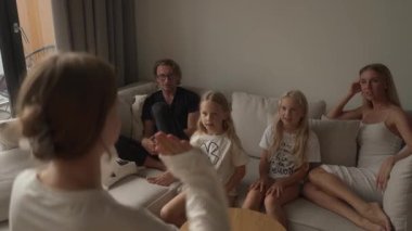 Bir aile evde sessiz sinema oynarken çok eğleniyor. Bir kız çocuğu ipuçlarını enerjik bir şekilde değerlendirirken ebeveynleri ve kız kardeşleri büyük bir heyecanla tahmin ediyor. Hatta bir kız neşeyle zıplıyor..