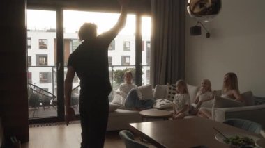 Bir baba evdeki sessiz sinema oyununda ipuçlarını enerjik bir şekilde değerlendirir. Karısı ve üç kızı kanepeden izliyor, tahmin ediyor ve kahkaha anlarını paylaşıyorlar..