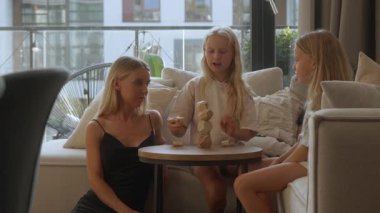 İki kızı olan anne evde yaratıcı bir eğitim oyunu oynuyor. Tahta blokları dikkatlice istifliyor. Bu aktivite dengeyi, iyi motor becerileri ve doğal oyuncaklarla öğrenmeyi geliştirir..