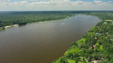 Polonya, Jachranka yakınlarında Narew Nehri ve Zegrze Reservoir. Geniş su genişliği, orman bankaları, evleri olan köy ve uzak altyapı. Parçalı bulutlu bir yaz günü.