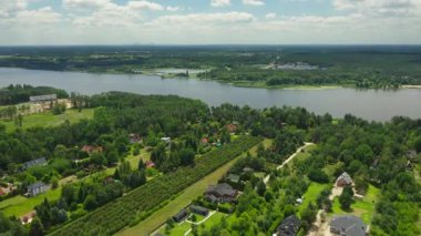 Narew Nehri kıyısındaki Serock 'taki bir Polonya köyü olan Jachranka' nın hava görüntüsüne yaklaşıyoruz. Sahnede evler, özel bahçeler, ağaçlık alanlar ve Varşova 'nın uzak olduğu geniş bir nehir yer alıyor..