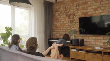 Heyecanlı bir aile oturma odasında sessiz sinema oynuyor. Genç çocuk enerjik bir şekilde ellerini arkasına alarak zıplar ve kanepeden gülen ve tahmin yürüten ebeveynlerine ipuçları verir..