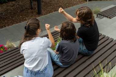 Bir anne ve iki oğlu, birbirlerine kenetlenmiş ellerini bir bankta sallıyorlar. Taş kağıt makas oyununun geri sayım evresine giriyorlar. Ortaya çıkmadan önce oyuncu bir belirsizlik yaratıyorlar..