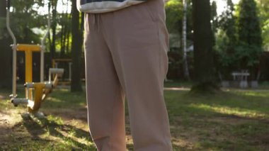 Genç bir kadın parkta gecekondu antrenmanına katılmış, egzersiz hareketini gösteriyor. Vücut gücü, sağlık ve enerjik bir yaşam tarzı için açık havada fiziksel aktivite.