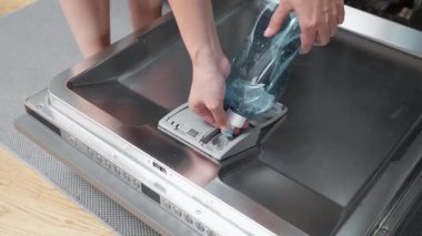 Eller dikkatle bir şişeden gelen suyu bulaşık makinesinin özel makinesine döker. Mutfak aletlerini hazırlamak en uygun temizlik ve pırıl pırıl, çıplak tabakları garantiler..