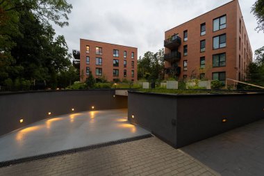 Modern bir yerleşim yerindeki yeraltı otoparkına kadar aydınlatılmış rampa. Kasaba sakinlerine güvenli, kullanışlı araç deposu sunuyor, şehir park ihtiyaçlarını karşılıyor. Şehir sakinleri için pratik konfor.