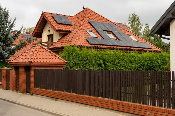Özel bir konutun çatısındaki güneş panelleri. Fotovoltaik sistem temiz enerji üreterek tasarruf ve kendi kendine yeterlilik sağlıyor. Geleneksel çatı yapımında modern sürdürülebilir teknoloji.