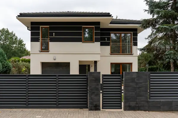 Ultra modern ev: kalın mimari tasarım, karşıt cephe, geniş pencereler. Egemen koyu renk çitler, bu çağdaş evin özel bölgesini tanımlayan yüksek güvenliği sağlar..