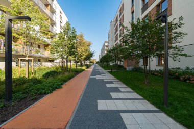 Modern bir konut kompleksinin peyzajlı bir eğlence sokağı. Bu alan bir yaya geçidi ve gelişimin kolaylıklarının bir parçası olan bisikletlere ayrılmış ayrı bir şerit içeriyor..