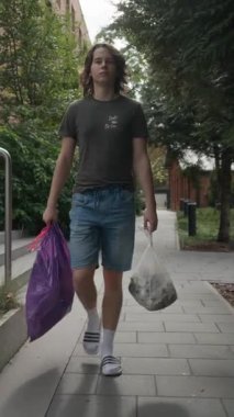 Genç bir adam çöpü çıkarmak için kaldırım boyunca yürür, iki çöp torbası taşır. Bu günlük ev işleri sorumluluk, atık yönetimi ve geri dönüşüm kavramlarını temsil etmektedir..