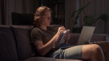 Bir öğrenci gece geç saatlere kadar çalışır, dizüstü bilgisayar kullanır ve bir deftere yazı yazar. Çevrimiçi bir konferanstan notlar alıyor ya da araştırma yapıyor, son teslim tarihine kadar eğitimine odaklanıyor..